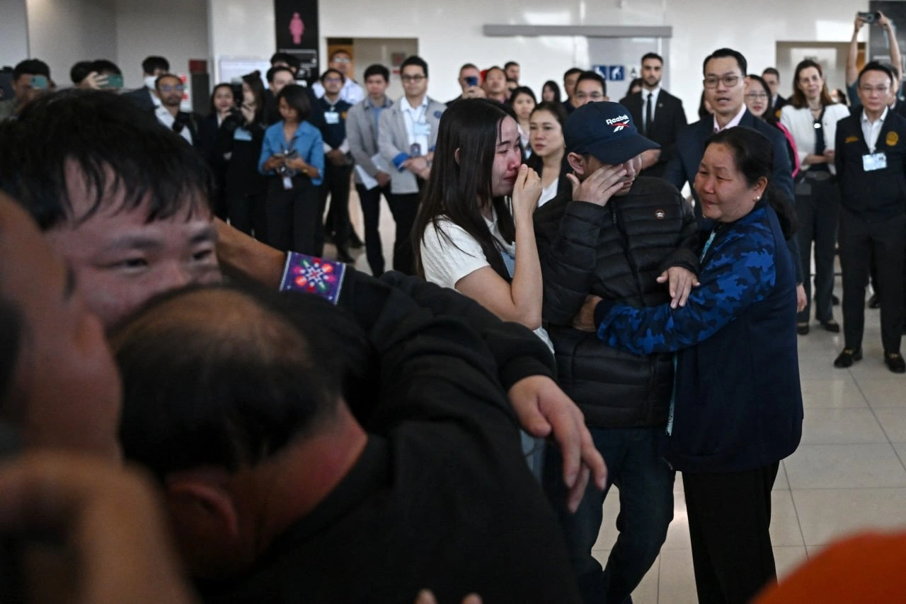 Freed Thai nationals with Foreign Minister Maris Sangiampongsa, third from right, and other officials at Bangkok airport on February 9, 2025 [Manan Vatsyayana/AFP]